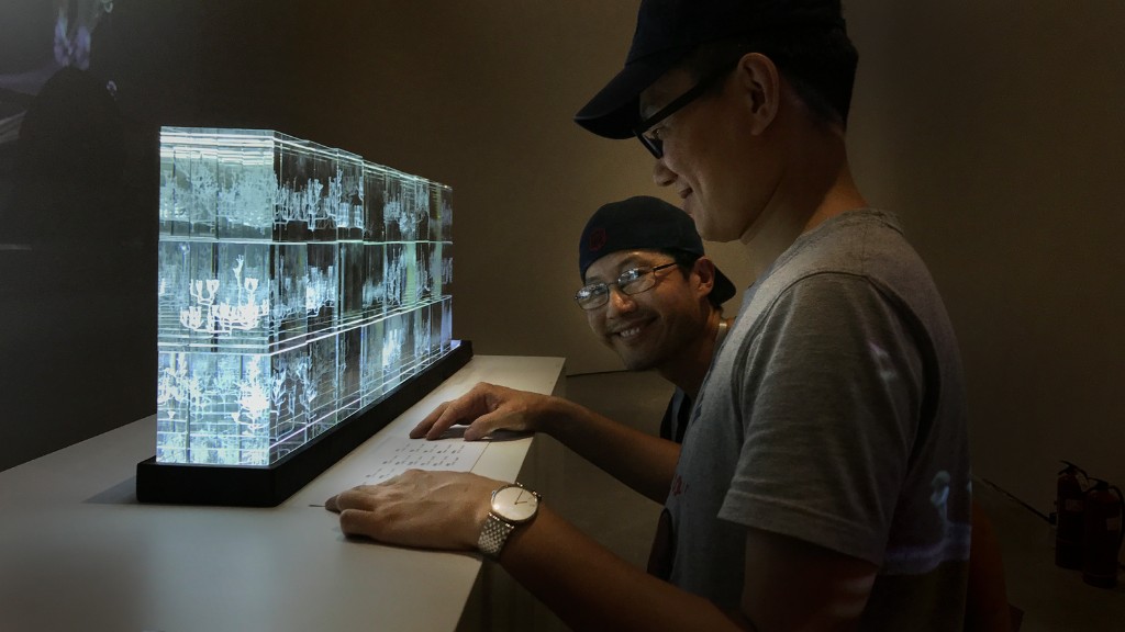 Visitors viewing a layered glass family-tree sculpture at the National Museum of China